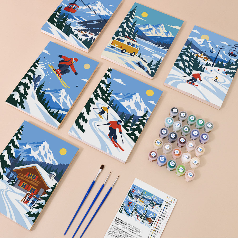 six illustrated scenes depicting winter sports activities, including skiing and snowboarding, set against snowy mountain landscapes. There are also paintbrushes and paint tubes arranged on a table, suggesting that the scene is a painting kit for creating winter sports-themed artwork.