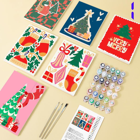 various Christmas-themed items, including greeting cards, paints, and brushes, arranged on a table.