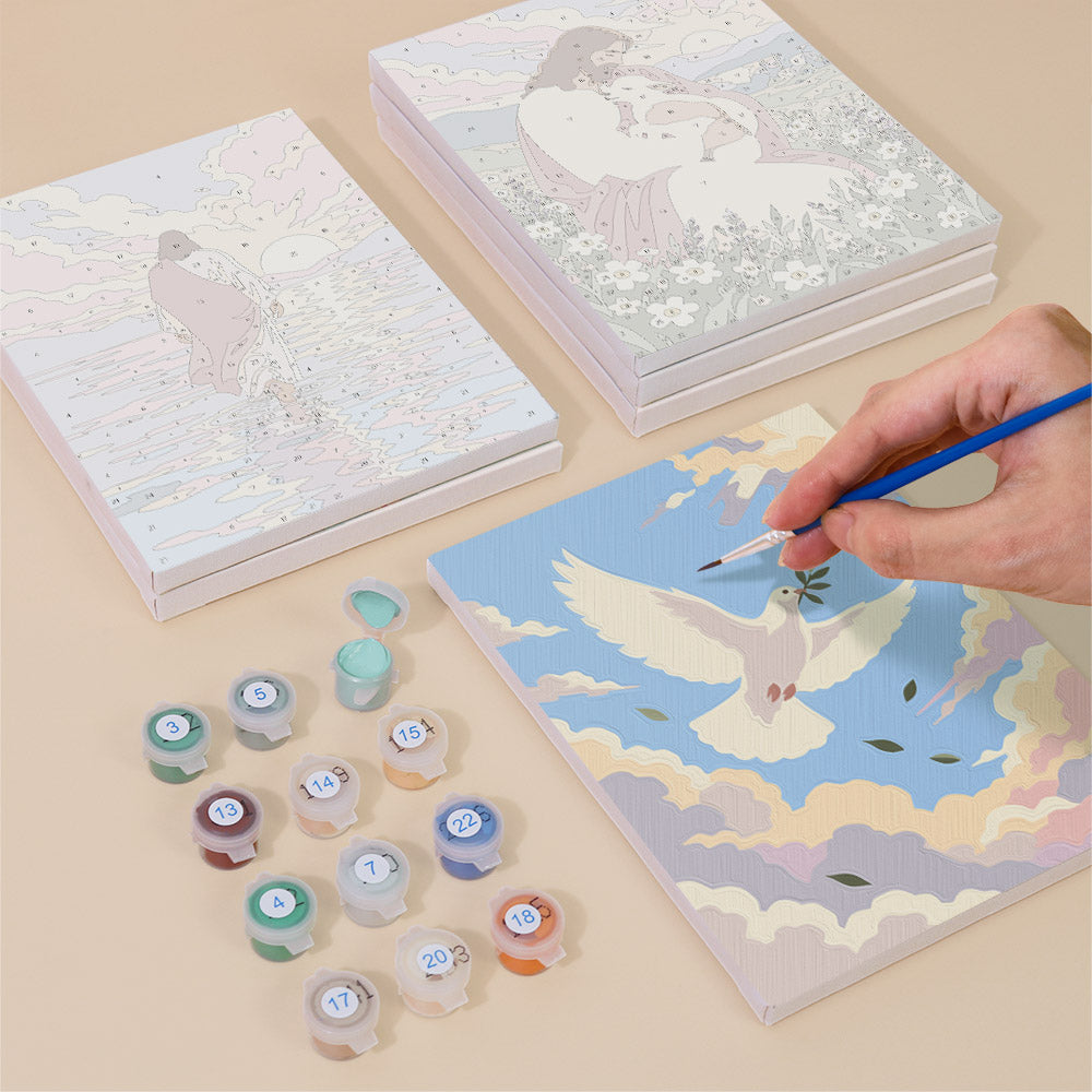 a person's hand painting a picture of a bird in flight on a canvas, surrounded by various art supplies such as paint bottles and a palette.