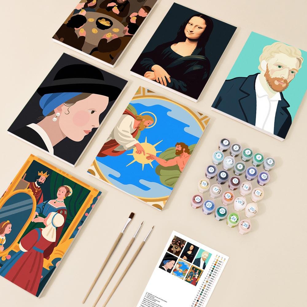 various art supplies, including paintbrushes, paint tubes, and a book, arranged on a table.