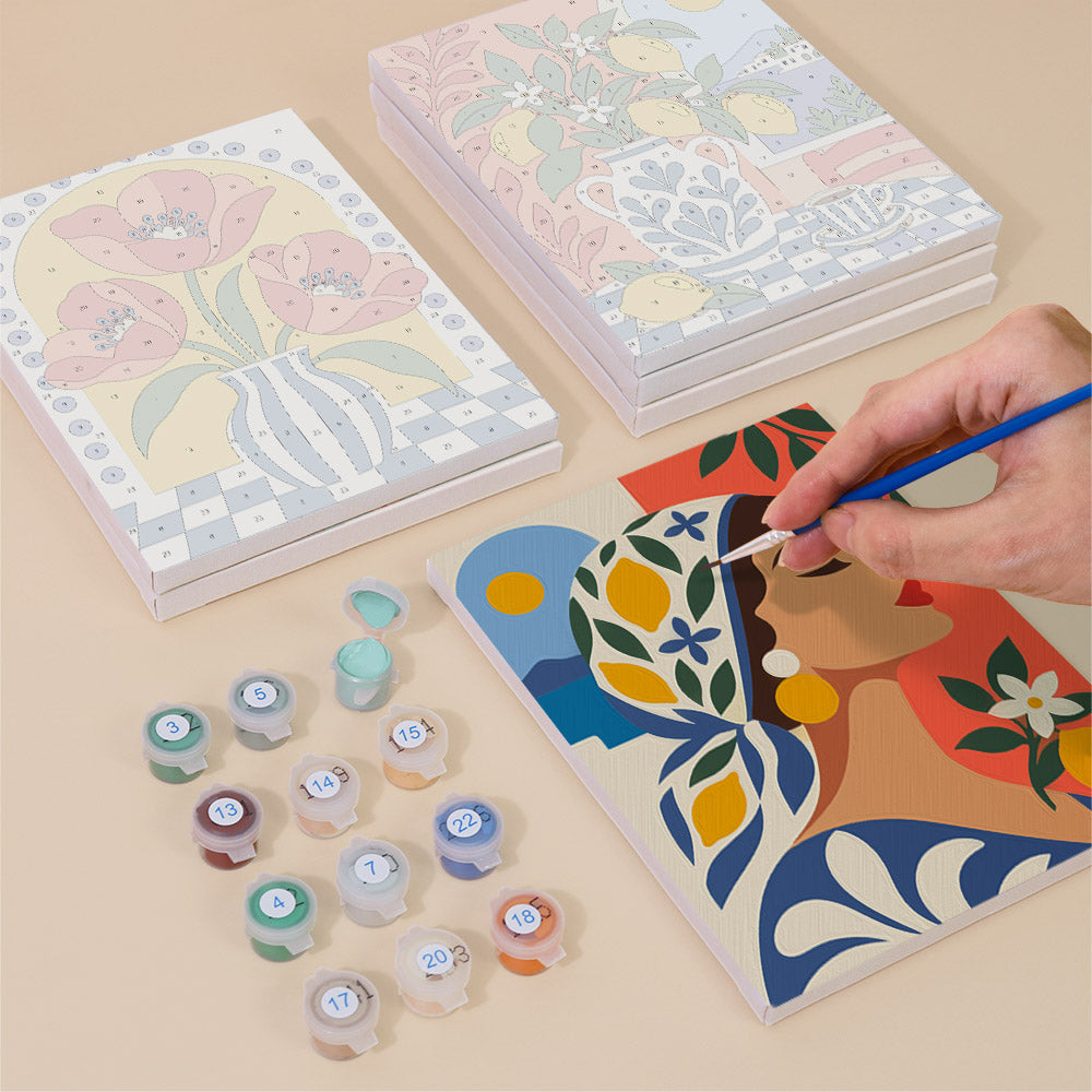 a person's hand painting a colorful abstract artwork on a canvas, surrounded by various art supplies such as paint tubes and a sketchbook.