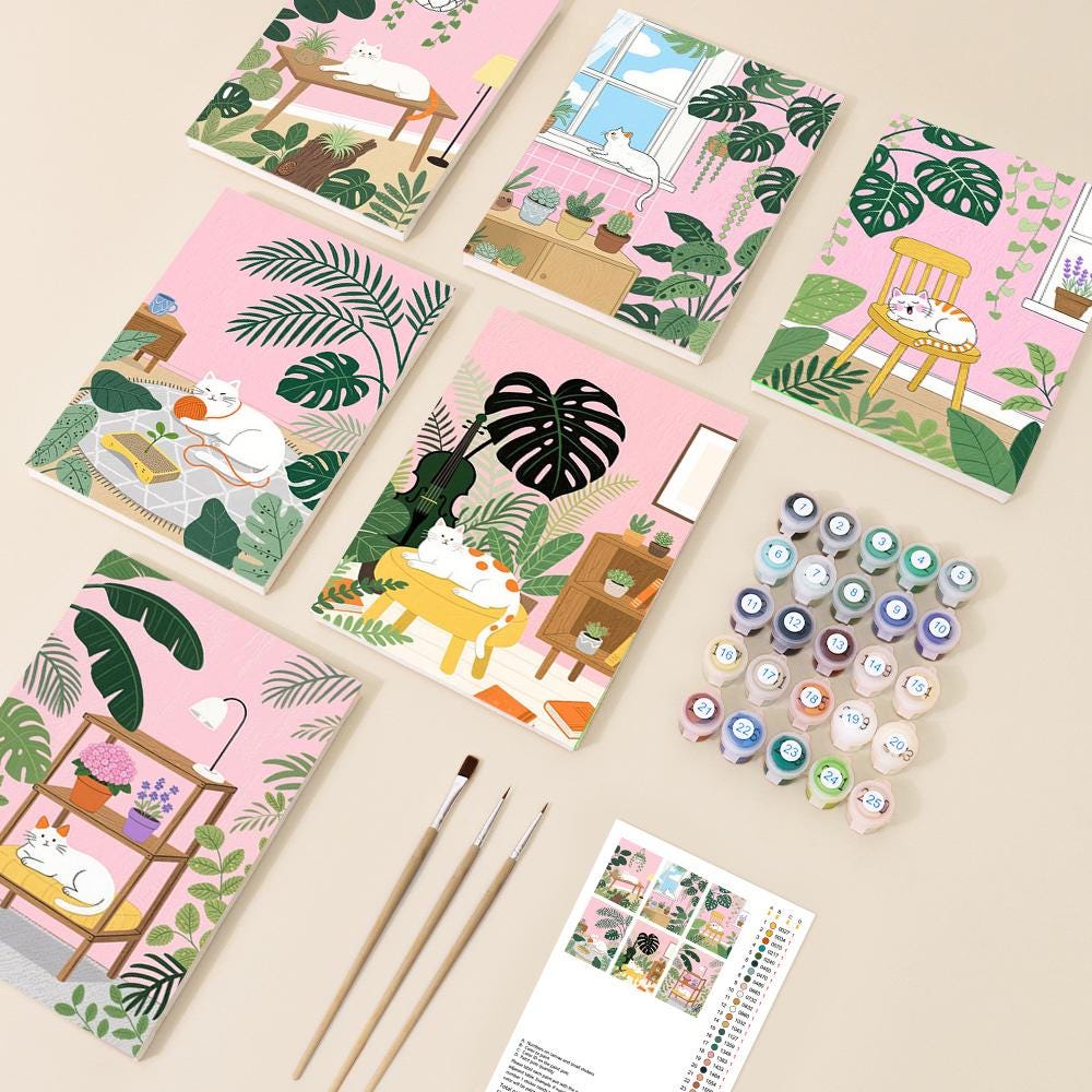 a collection of illustrated notebooks, paintbrushes, and paint tubes arranged on a light-colored surface.