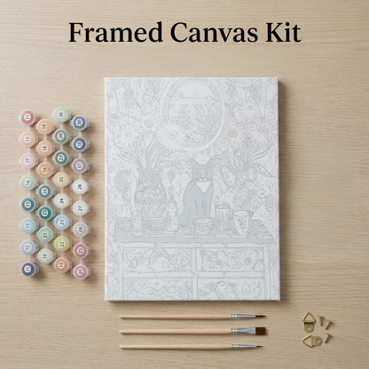 a framed canvas kit with a detailed illustration of a cat sitting on a table, surrounded by various art supplies such as paintbrushes and paint tubes.