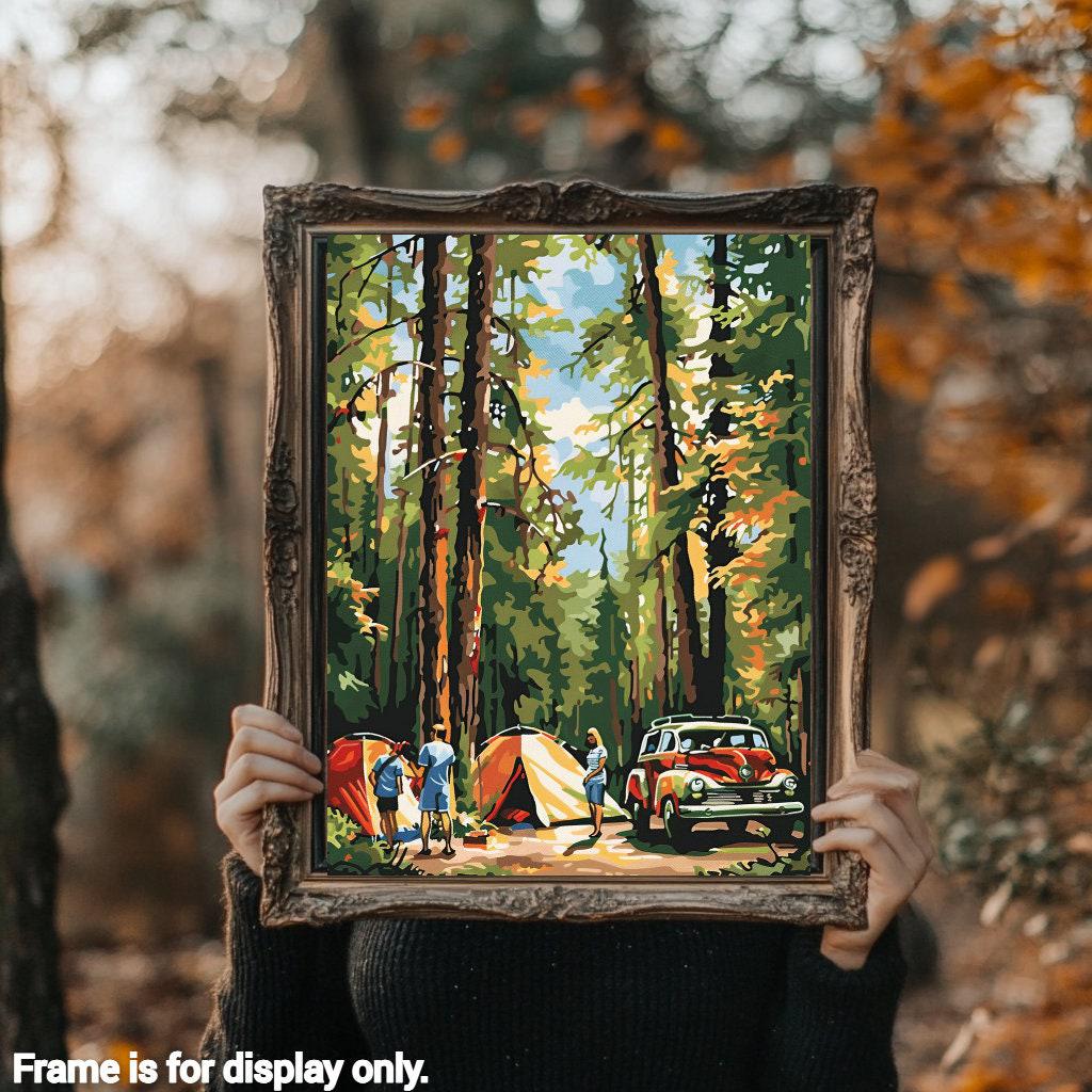 a woman holding up a painting of a camping scene