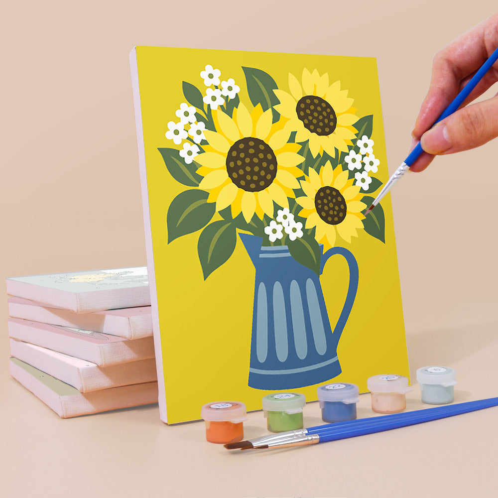A hand is painting a yellow canvas depicting a vase with flowers, using a paintbrush and a palette of colors.