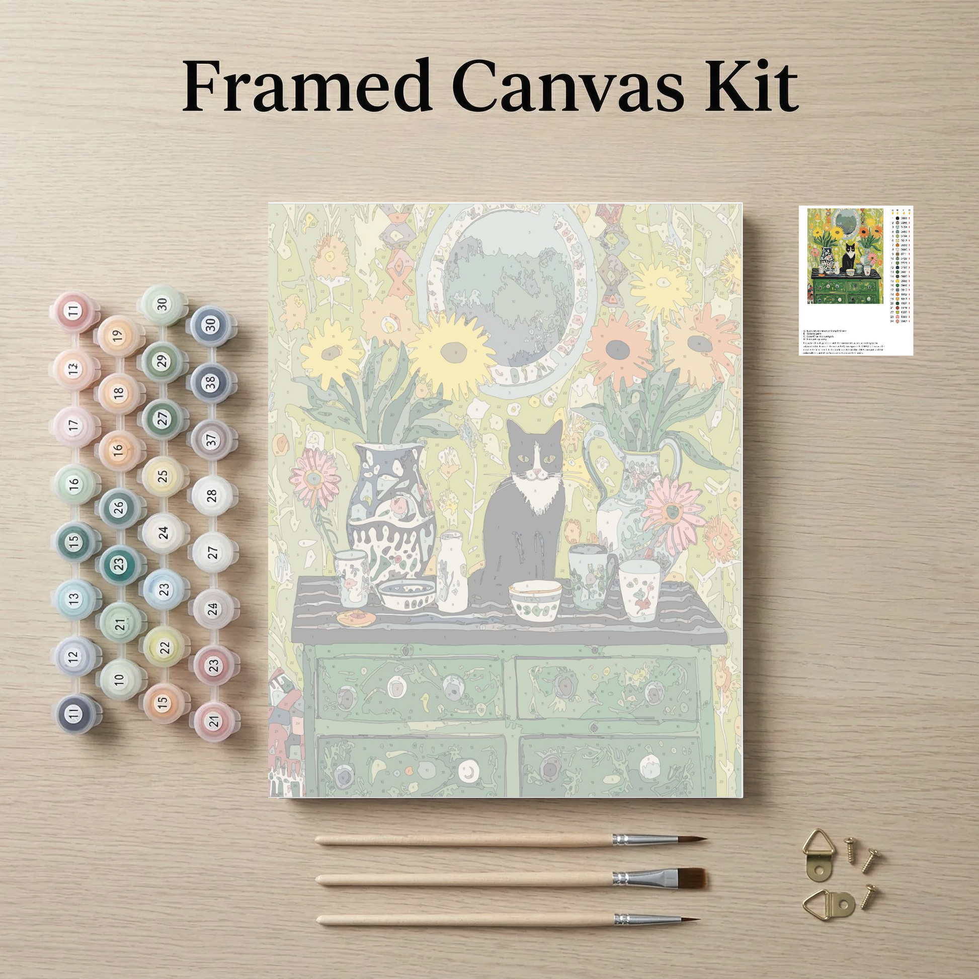 The image is a framed canvas kit featuring a painting of a cat sitting on a table surrounded by various objects, such as vases, cups, and a clock. The kit also includes paintbrushes, paint tubes, and a small picture frame.