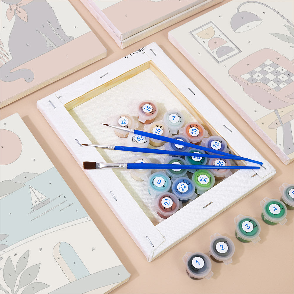 a painting kit with a canvas, paintbrushes, and multiple paint color bottles, all arranged on a table.