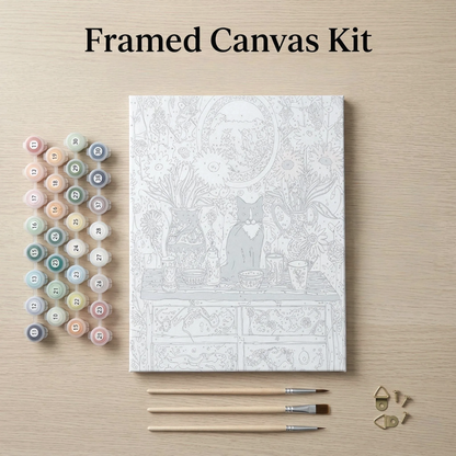 a framed canvas kit with a detailed illustration of a cat sitting on a table, surrounded by various art supplies such as paintbrushes and paint tubes.