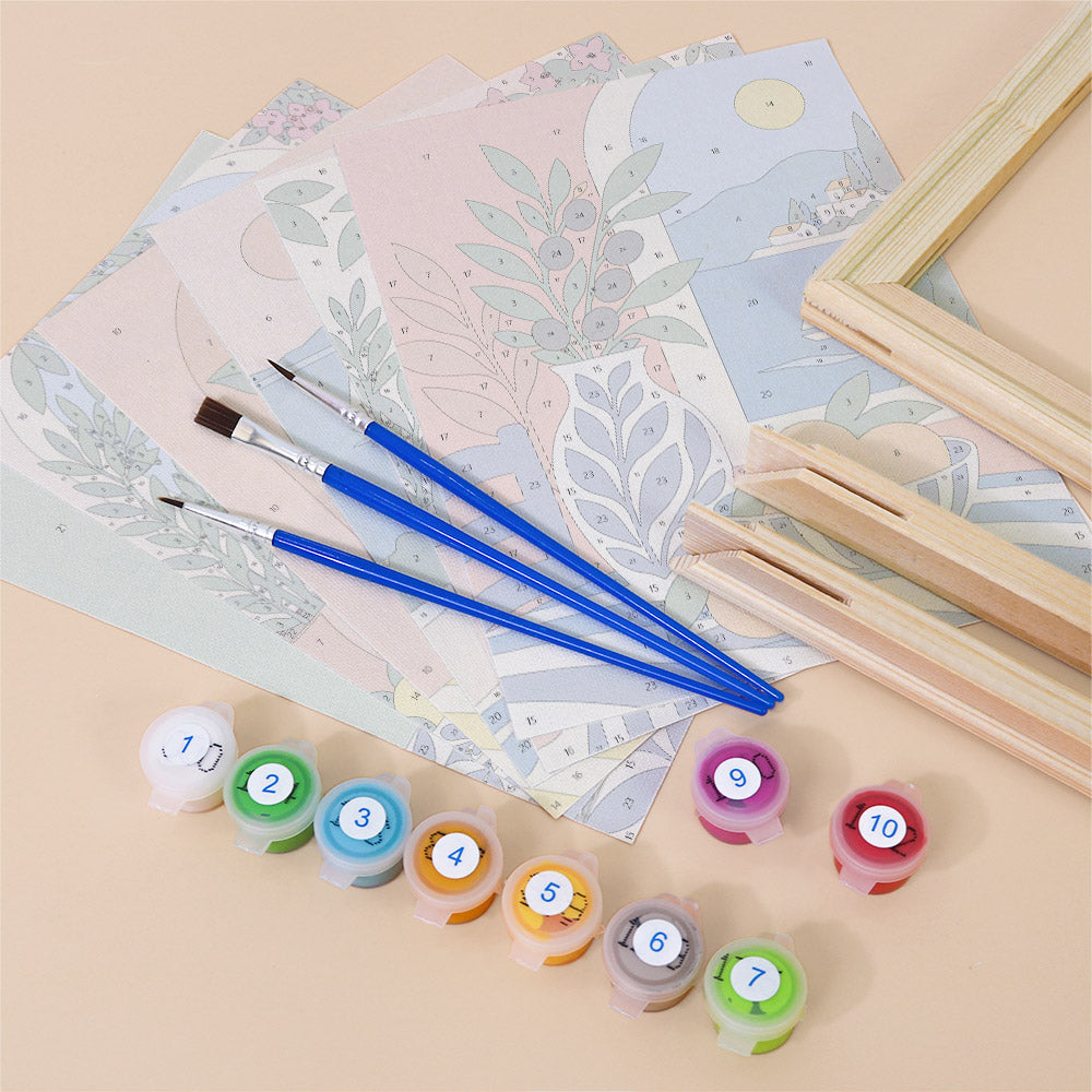 various art supplies, including paintbrushes, paint tubes, and a sketchbook, arranged on a light-colored surface.