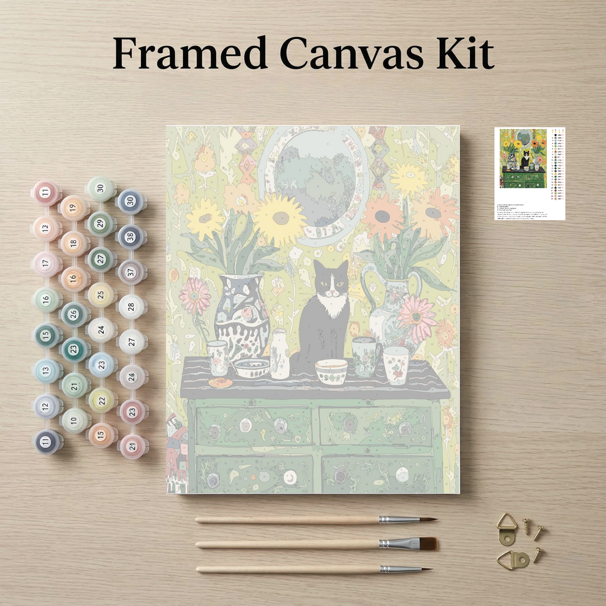 The image is a framed canvas kit featuring a painting of a cat sitting on a table surrounded by various objects, such as vases, cups, and a clock. The kit also includes paintbrushes, paint tubes, and a small picture frame.