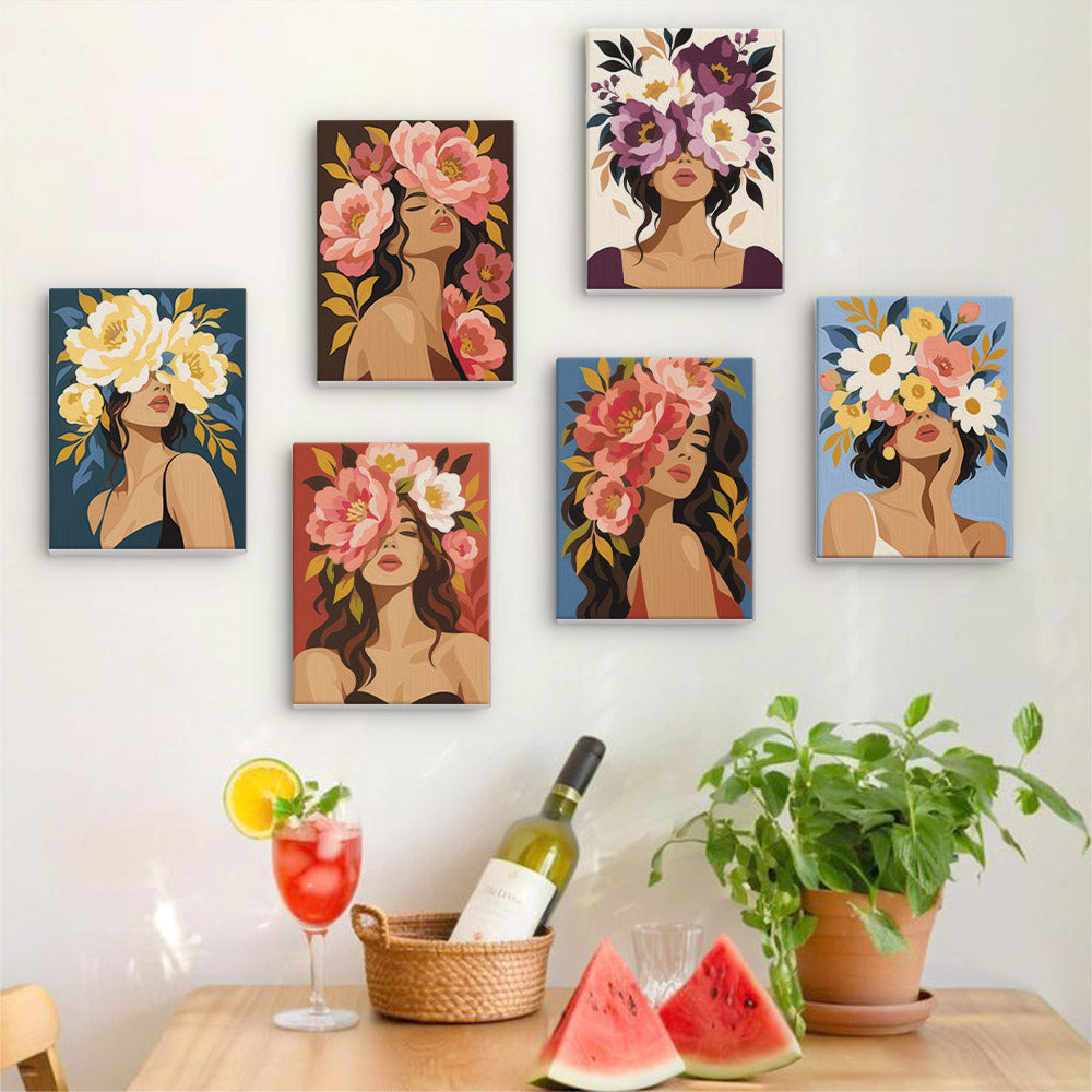 a wall with six framed paintings of women with floral headpieces, arranged in a grid pattern. Below the paintings, there is a table with a wine bottle, a glass, and a basket of watermelon slices.