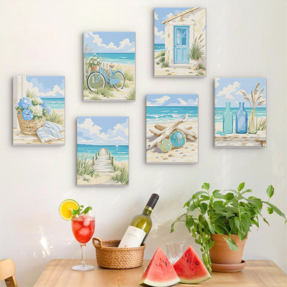 a wall adorned with six paintings depicting beach scenes, including a bicycle, a house, a basket of flowers, a wooden dock, a blue bottle, and a glass of water with a lemon slice. The paintings are arranged in a grid-like pattern on the wall, creating a visually appealing and harmonious display.
