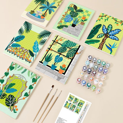 various art supplies, including paintbrushes, paint tubes, and a sketchbook, arranged on a light-colored surface.