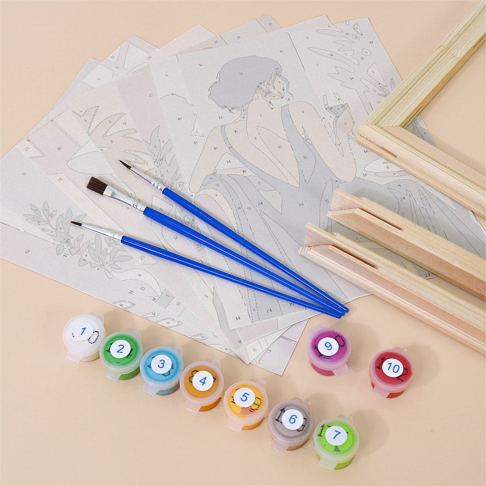 various art supplies, including paintbrushes, paint tubes, and a sketchbook with a painting of a woman on it.