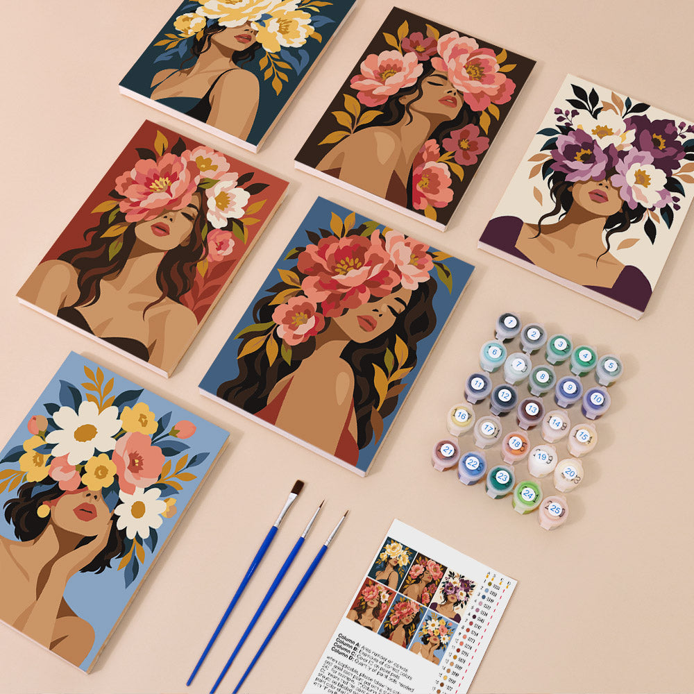 various art supplies, including paintbrushes, paint tubes, and a book with instructions for a painting activity. The supplies are arranged on a table, suggesting that they are being prepared for an artistic project.
