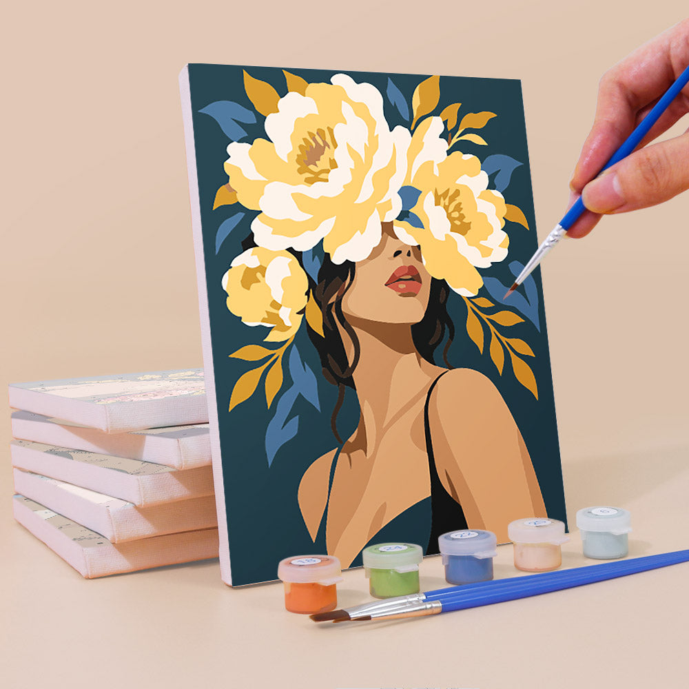 a painting of a woman with a large floral headdress, surrounded by various art supplies such as paintbrushes and paint tubes.
