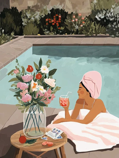 A woman in a pink towel relaxes by a pool, holding a drink and surrounded by a vase of flowers and a book.