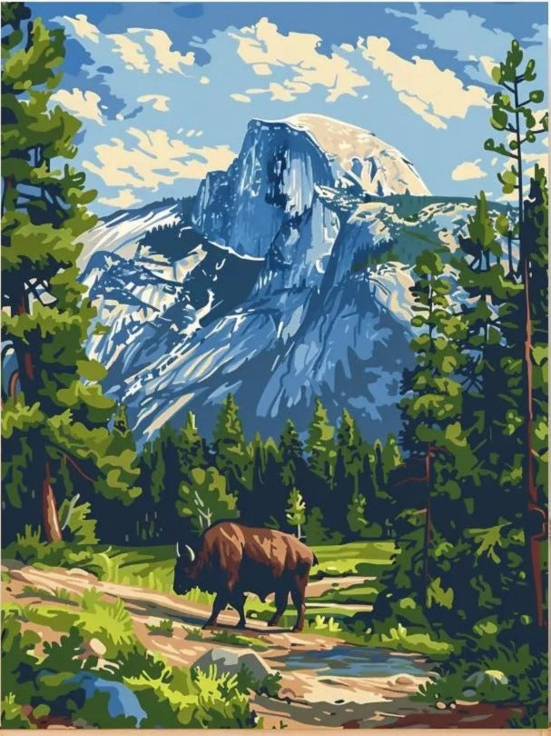 A bison is walking on a dirt path through a lush forest, with a majestic mountain range in the background.