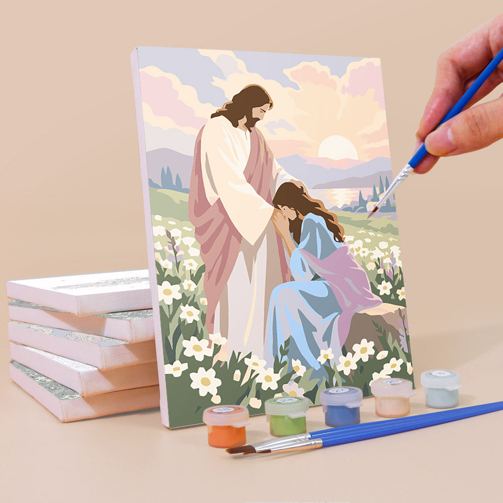 A hand is painting a religious scene featuring a figure of Jesus Christ surrounded by flowers and a woman, with a paintbrush in hand.