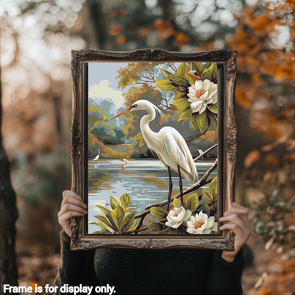 a woman holding up a painting of a white bird