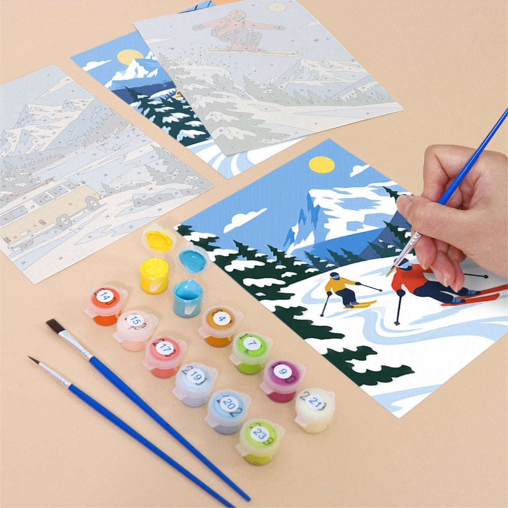 a hand painting a winter scene with skiers and snow-covered mountains, using a paintbrush and a palette of colors.